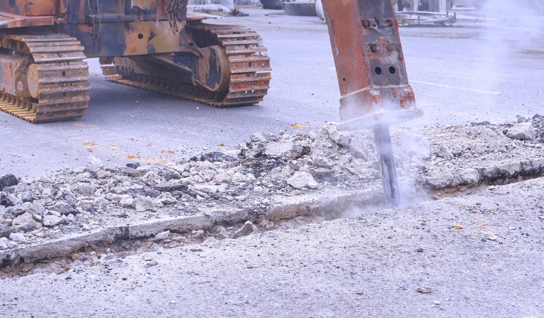 Construction equipment drilling into concrete surface to prepare space for concrete cutting.